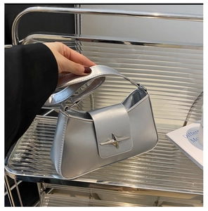 Detail of silver metallic shoulder bag with cross star buckle and mirror finish texture