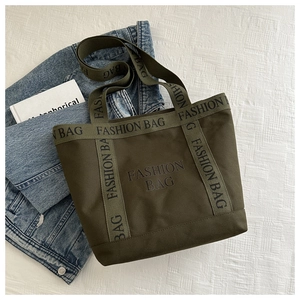 Vue à plat d'un sac cabas en toile vert armée avec inscription FASHION BAG et veste en jean
