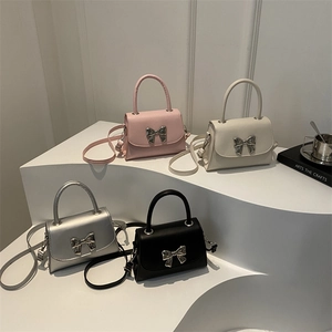Bow accent mini crossbody handbags in pink, white, silver and black displayed on white steps