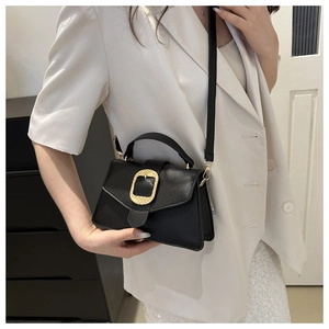 Detail of black lychee grain leather handbag with textured gold buckle and crossbody strap