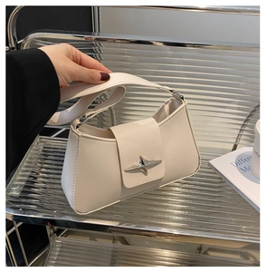 Detail of silver star-shaped metal buckle on creamy white leather underarm bag