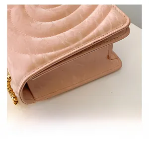 Close-up of pink quilted crossbody bag with marble texture and gold chain detail