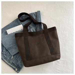 Détail du grand sac cabas en toile marron foncé avec texte imprimé sur fond gaufré