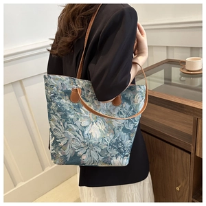 Detail of floral jacquard pattern and brown leather strap on vintage tote bag