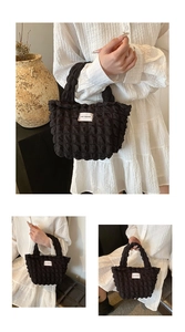 Detail of black popcorn texture tote bag with LOVE FASHION label and pleated handle
