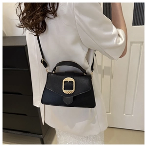 Detail of black pebbled leather crossbody bag with oversized gold square buckle