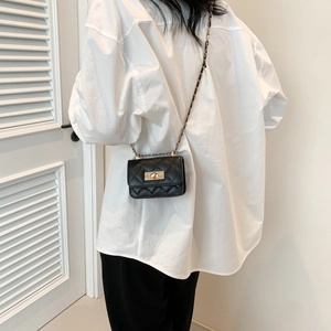 Quilted black chain crossbody bag with gold twist lock shown on a female model