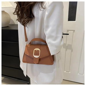 Detailed macro of caramel lychee leather texture and large metal buckle on the shoulder bag