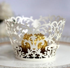 Detail view of white laser-cut cake wrapper with elegant lace vine patterns on a plate