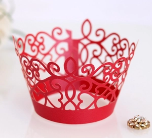 Macro detail of red laser-cut vine and heart lace pattern on a cupcake wrapper