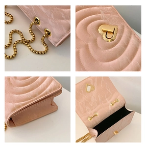 Close-up of pink quilted crossbody bag with heart-shaped lock and gold chain strap