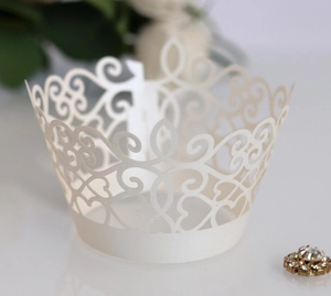 Macro shot of laser-cut white lace cupcake wrapper with heart and swirl patterns