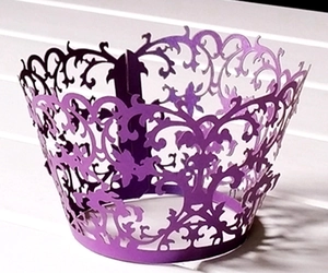 Detail of purple laser-cut cupcake wrapper with intricate pearlescent floral lace pattern