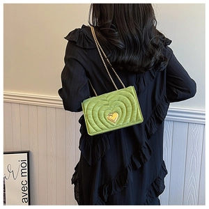 Macro shot of green heart-quilted leather bag featuring a gold heart-shaped metal lock