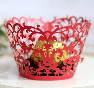 Macro detail of red laser-cut lace cupcake wrapper with elegant vine pattern for weddings