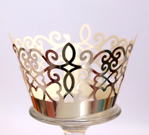 Macro detail of laser-cut crown lace cupcake wrapper in champagne gold finish