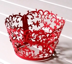Detail of red laser-cut cupcake wrapper showing intricate floral lace vine patterns