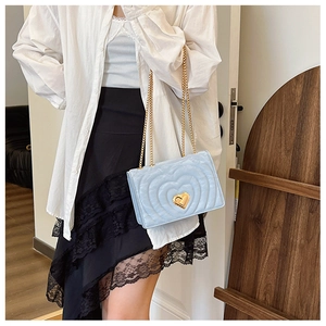 Detail of light blue crossbody bag featuring heart quilting and gold heart-shaped metal clasp