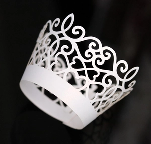 Detail of white laser-cut cupcake wrapper featuring elegant crown and heart patterns