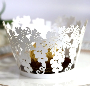 Detail of laser-cut pearl white cupcake wrapper with elegant grape patterns and gold chocolate