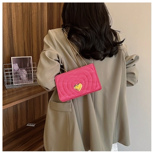 Detail of hot pink crossbody bag with heart quilting and golden heart-shaped clasp