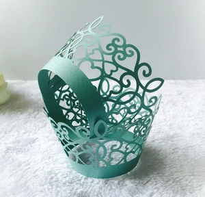 Intricate laser-cut teal cupcake wrapper with heart and vine patterns for party decor