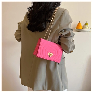Detail of rose red heart-quilted chain bag with a gold heart-shaped metal twist lock