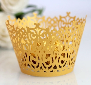 Close-up of golden laser-cut cupcake wrappers with intricate hollow floral patterns