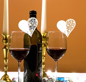 Elegant white laser-cut heart paper place cards on wine glass for wedding decorations