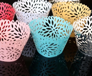 Laser-cut cupcake wrappers with intricate floral patterns in various elegant colors