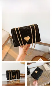 Close-up of golden heart lock and metallic chain on black velvet crossbody bag