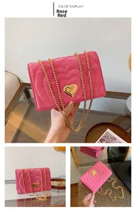 Detail of rose red crossbody bag with heart-quilted texture and gold heart-shaped lock