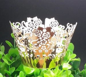 Detail of golden laser-cut cupcake wrapper with elegant rose and heart patterns