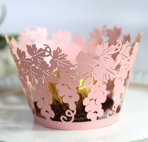 Pink laser-cut cupcake wrapper with grape leaf patterns around gold-wrapped chocolate