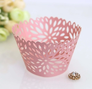 Macro shot of pink laser-cut cupcake wrappers with floral patterns and pearl finish