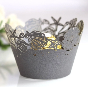 Dark grey laser-cut cupcake wrappers with intricate ocean shell and starfish patterns