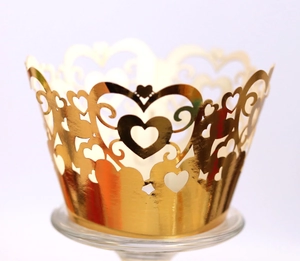 Detailed laser-cut golden cupcake wrapper featuring hollow heart and vine patterns