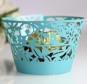 Teal laser-cut lace cupcake wrappers with intricate floral vine patterns for party decor