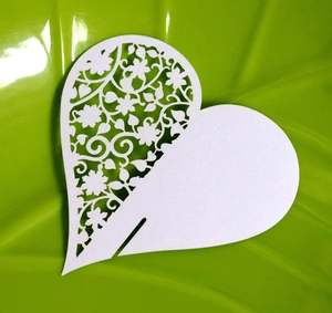 Detailed laser-cut heart-shaped paper place card with delicate floral pattern on white cardstock