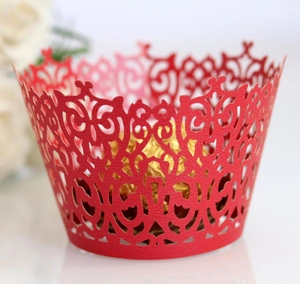 Macro shot of red laser-cut cupcake wrapper with vine patterns for wedding decoration