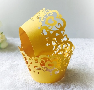 Detail of yellow laser-cut cupcake wrappers with heart lace patterns on plush fabric