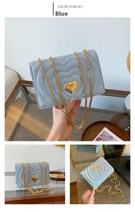 Detail of light blue quilted chain bag with heart stitching and golden heart-shaped twist lock