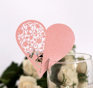 Close-up of pink laser-cut heart wine glass card with floral patterns for weddings