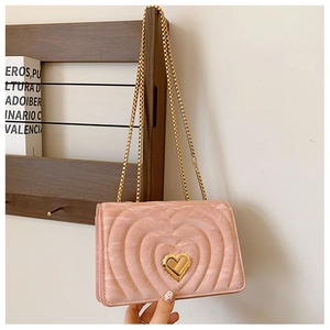Detailed view of pink heart-quilted crossbody bag with a golden heart-shaped metal lock