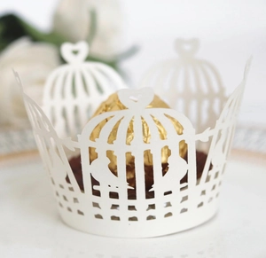 Close-up of white laser-cut cupcake wrappers with birdcage and heart patterns