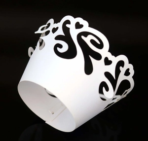 Macro detail of white laser-cut cupcake wrapper with heart and scroll hollow patterns