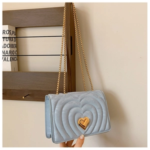 Close-up of light blue chain bag featuring heart-shaped quilting and a gold metal twist lock