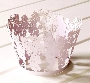 Detail of laser-cut paper cupcake wrappers featuring elegant grape and leaf vine patterns