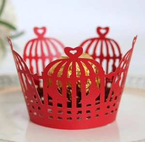 Macro detail of red laser-cut cupcake wrapper featuring birdcage and heart motifs