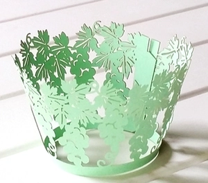 Detail of light green laser-cut grapevine paper cupcake wrappers for bakery cakes